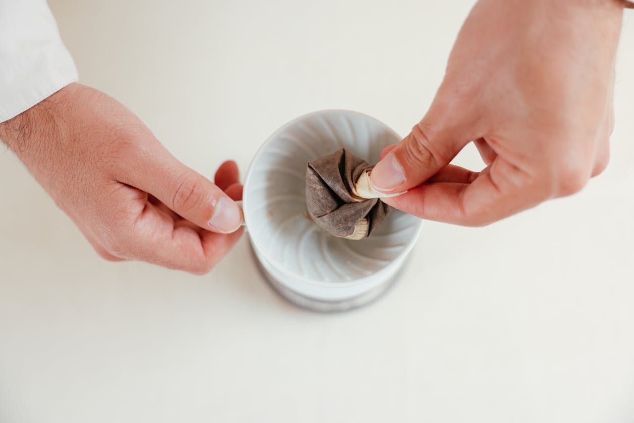 Two hands setting up a coffee filter in a ceramic dripper, ready for brewing.