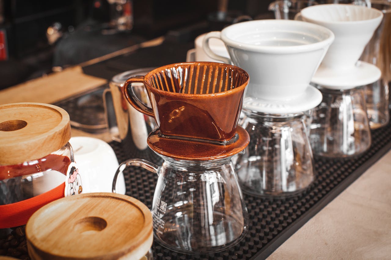 Array of ceramic and glass coffee drippers on display in a cozy coffee shop setting.
